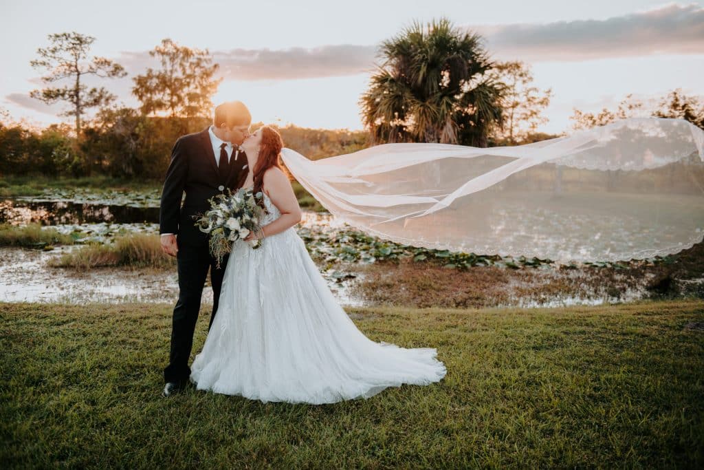 bride and groom kissing at the golden hour with veil floating in the wind at Wanderlust Okto