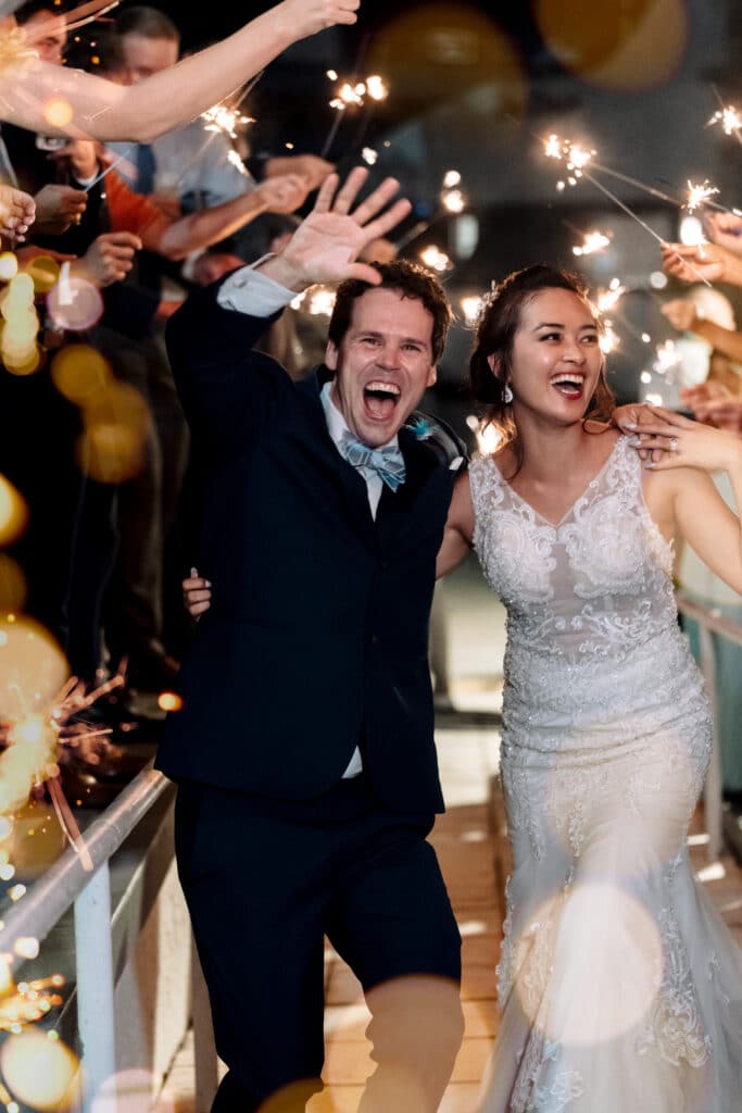 photo by Bouquet Photography of bride and groom leaving their reception smiling and laughing under a sparkler exit