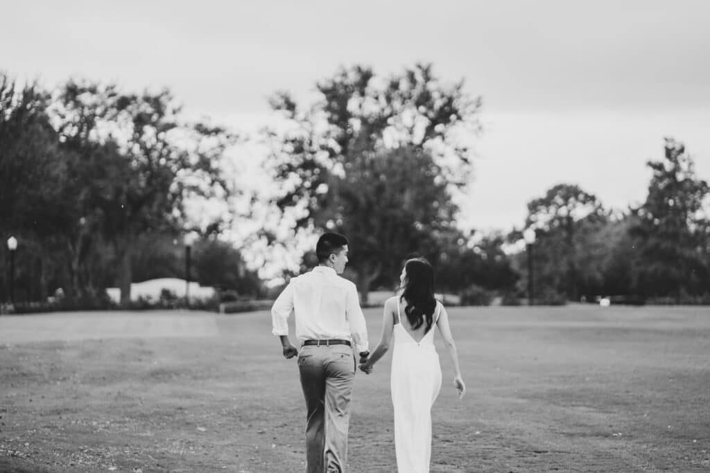black and white photo by Bouquet Photography of couples walking away through a field