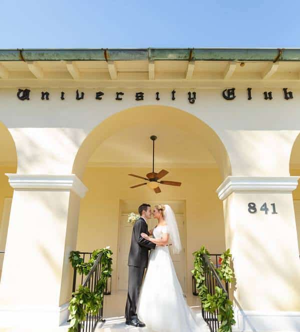 vride and groom kissing under arch at The University Club of Winter Park