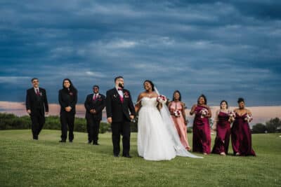 photo by Taylor Kuperberg Photography of weding party under a blue sky with bride and groom smiling at each other