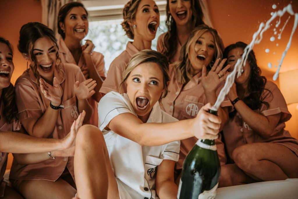 bride popping champange with bridesmaids in bridal ready room at Wanderlust Okto
