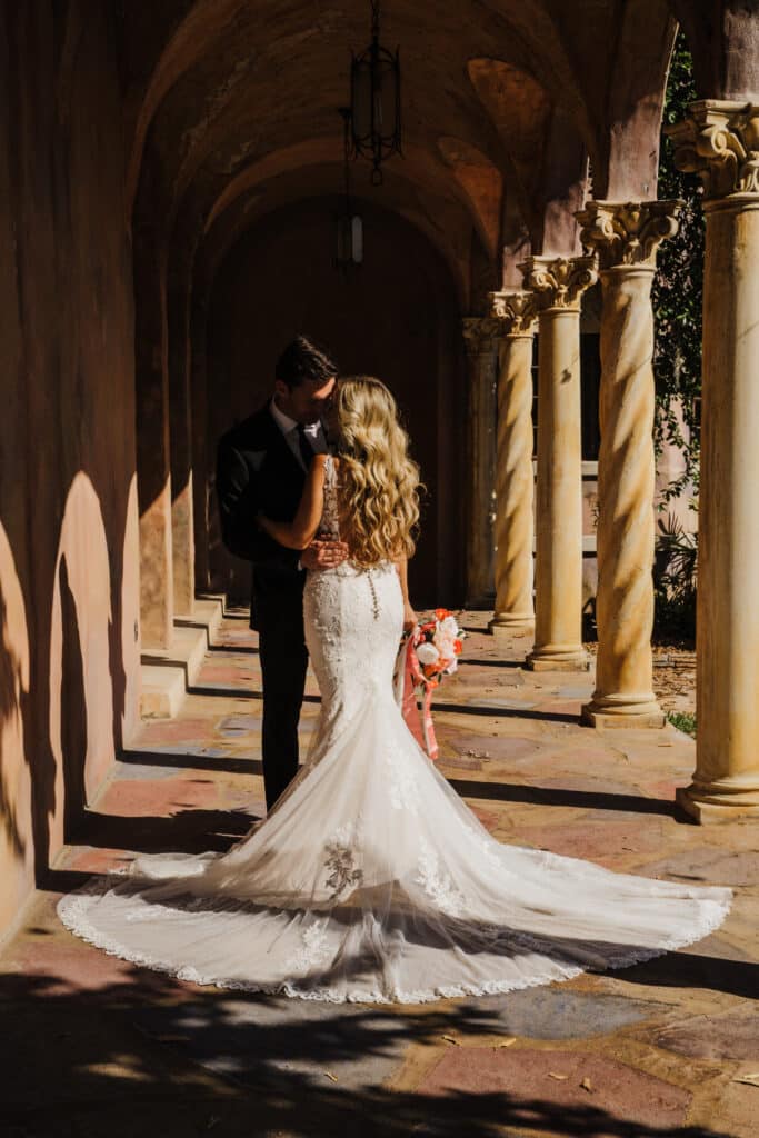 photo by Taylor Kuperberg Photography of bride and groom under stone archways on a stone path with bride's train spilling out behind her