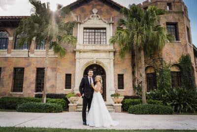 photo by Taylor Kuperberg Photography of bride and groom standing in front of Mediterranean stone building