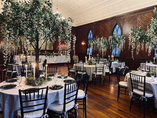 wedding reception with tall tree centerpieces on tables at THE 1883 Historic Venue