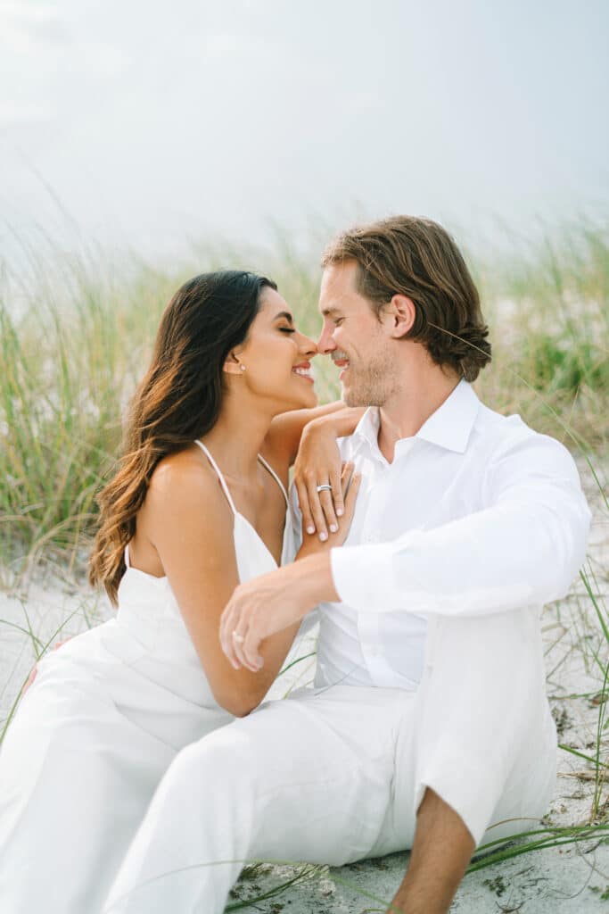 photo by Bouquet Photography of bride and groom sitting on a sand dune