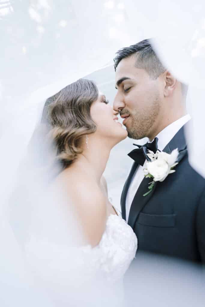 photo by Bouquet Photography of bride and groom kissing under a cloud of her veil