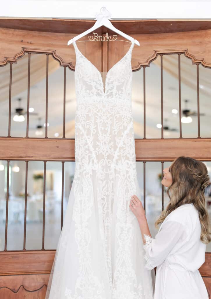 photo of bride looking up to her wedding dress hanging from a tall door by Sylvia Santos Photography