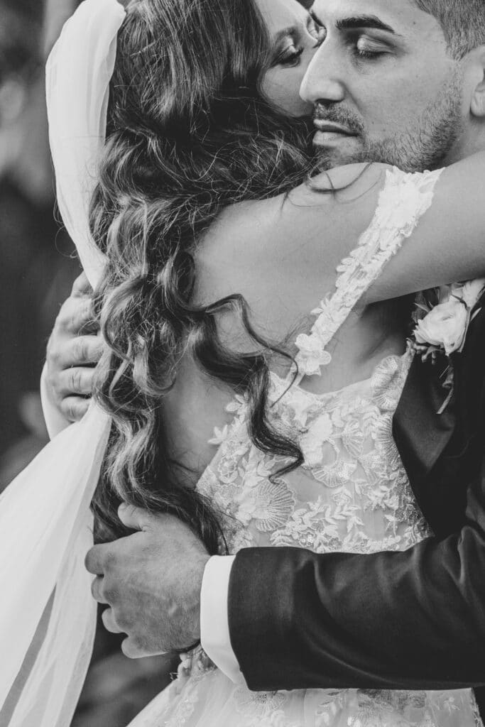 black and white photo by Bouquet Photography of bride and groom dancing and showing the lace of the brides dress and the curls of her hair