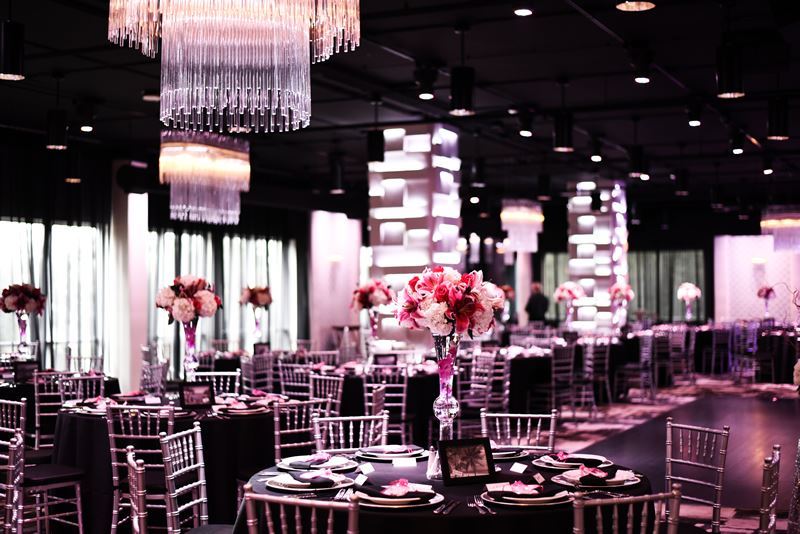 at The MEZZ reception setup with round tables, tall floral centerpieces under modern pillared lights