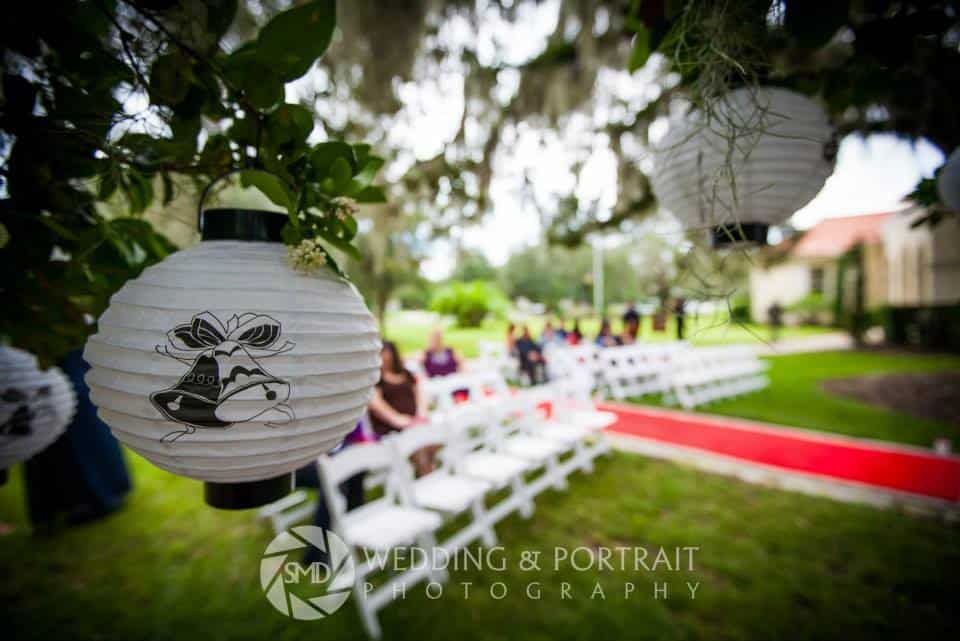 chinese lantern hanging in tree of outdoor ceremony with a red runner on the aisle at The University Club of Winter Park