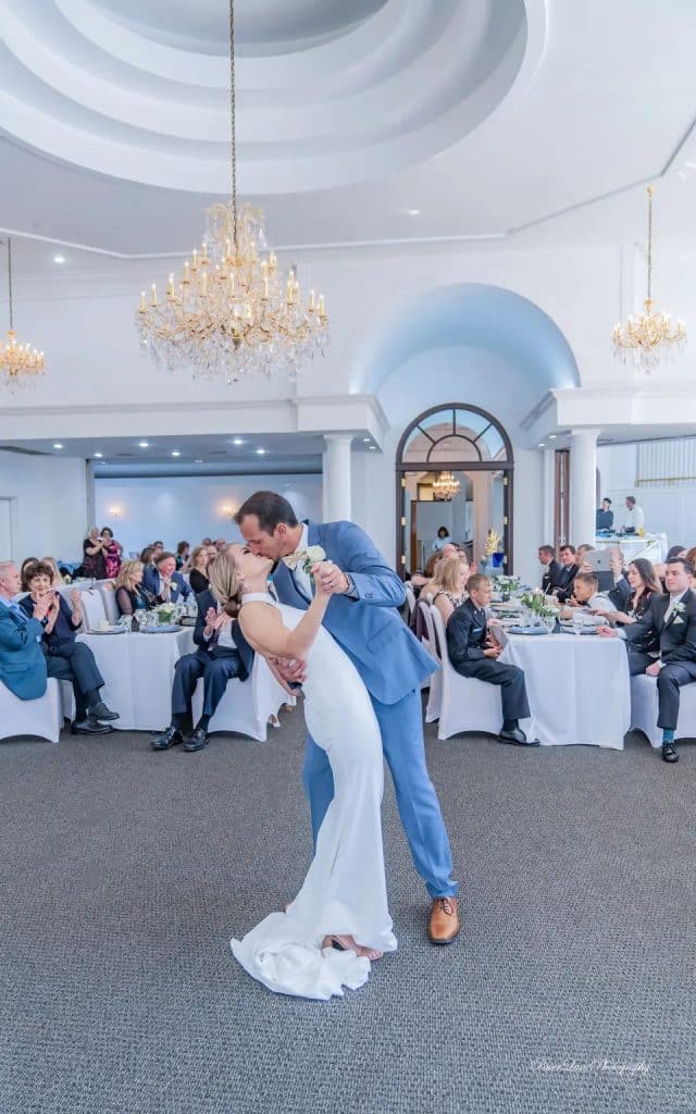 groom in light blue suite with brown shoes dipping and kissing bride at their first dance at La Cita Country Club