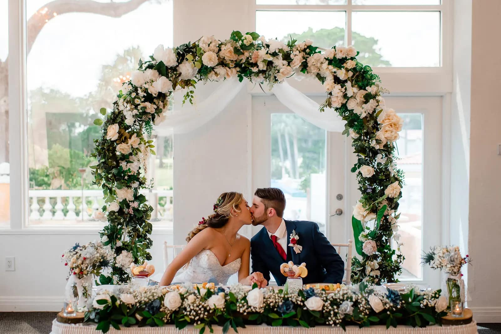 bride and groom kissing under arch of flowers at La Cita Country Club