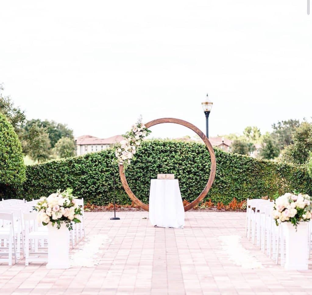 ceremony site with wooden arch bower and white floral spray at Omni Orlando Resort at Champions Gate