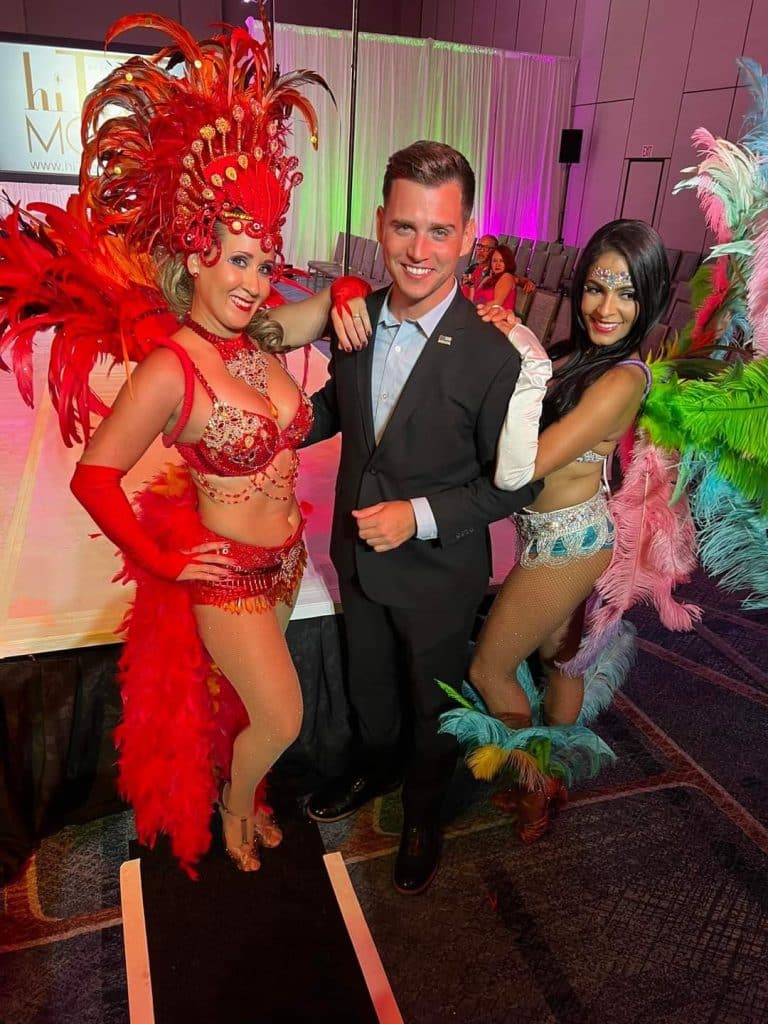man smiling with showgirls from Entertainment City Productions