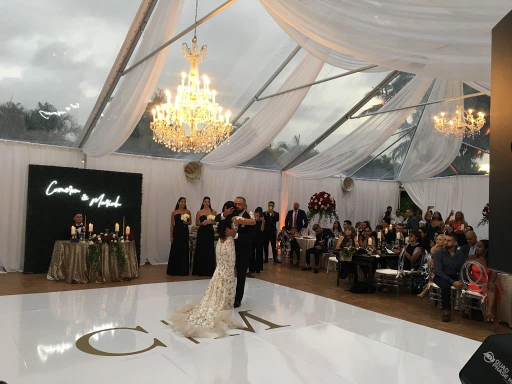 bride and groom dancing on floor with their initials, under draped ceiling, chandeliers and sunset with music by DJ Renier