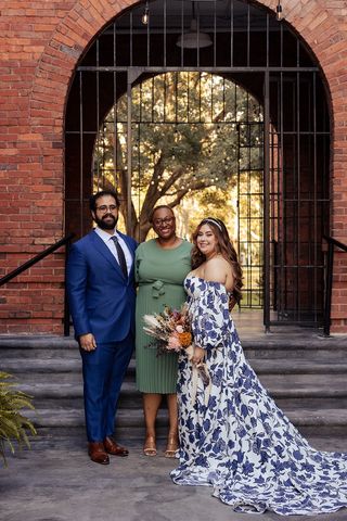 wedding couple with officiant from Abundant Notary Services in front of brick and rod iron arched building