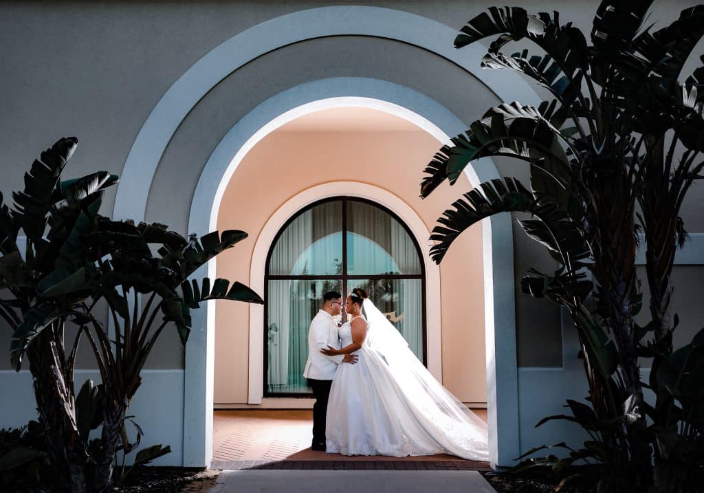 bride and groom kissing under repeating arches at Omni Orlando Resort at Champions Gate