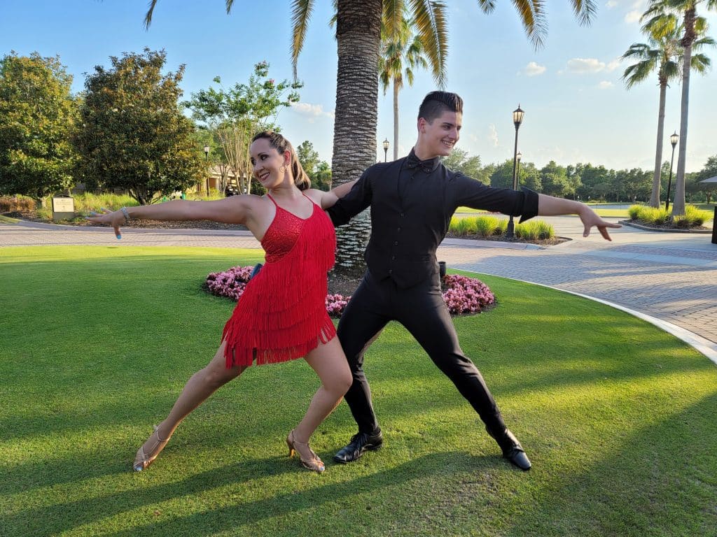 man in black and woman in red dress dancing salsa in the grass from Entertainment City Productions