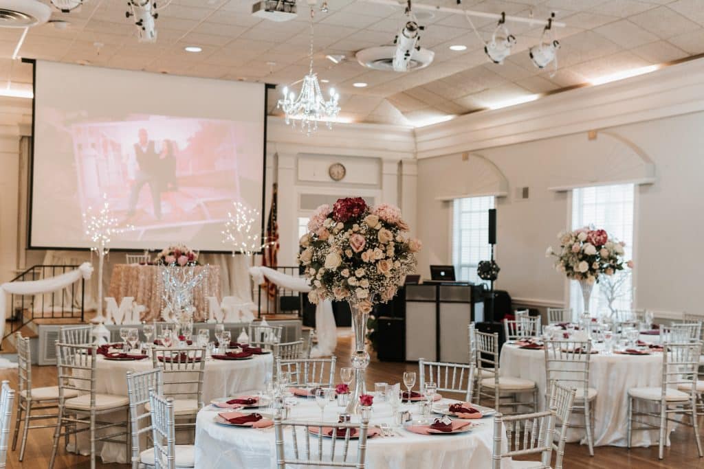wedding reception with white linen and screen for videos planned by Soulovevent LLC