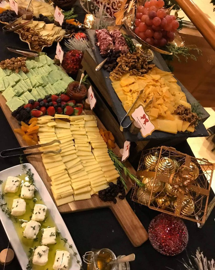 assorted cheese platter with crackers, grapes and strawberries by Uncommon Catering