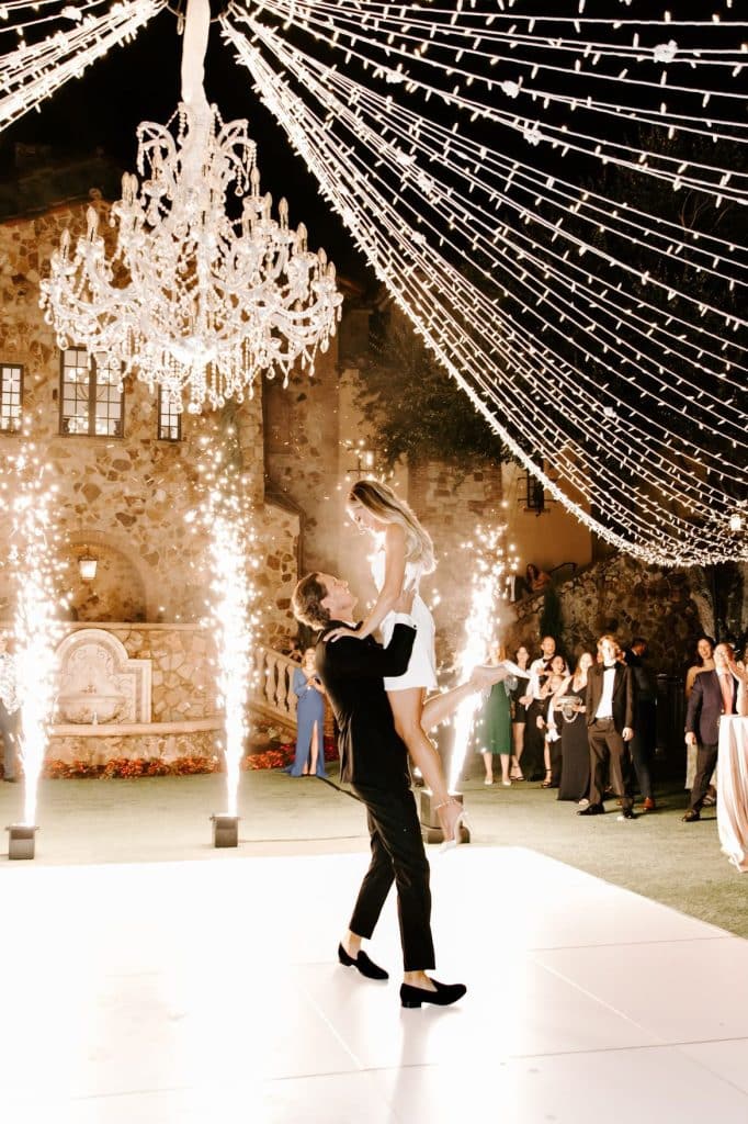 groom lifts bride on the dance floor at Bella Collina with cold sparks in the background