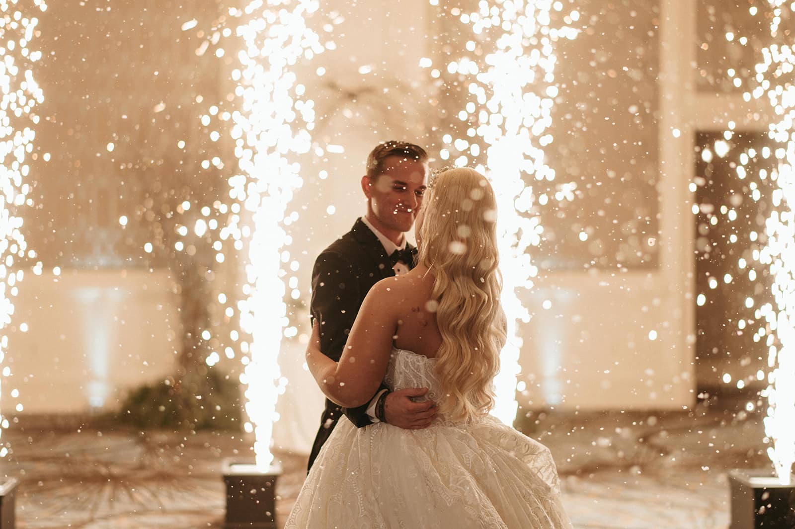 Newlywed couple dances on Four Seasons dance floor with cold sparks in the background