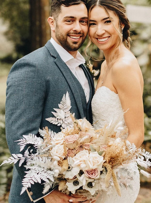 bride and groom smiling as bride holds champagne colored bouquet of ferns and flowers coordinated by Julie Miner Events
