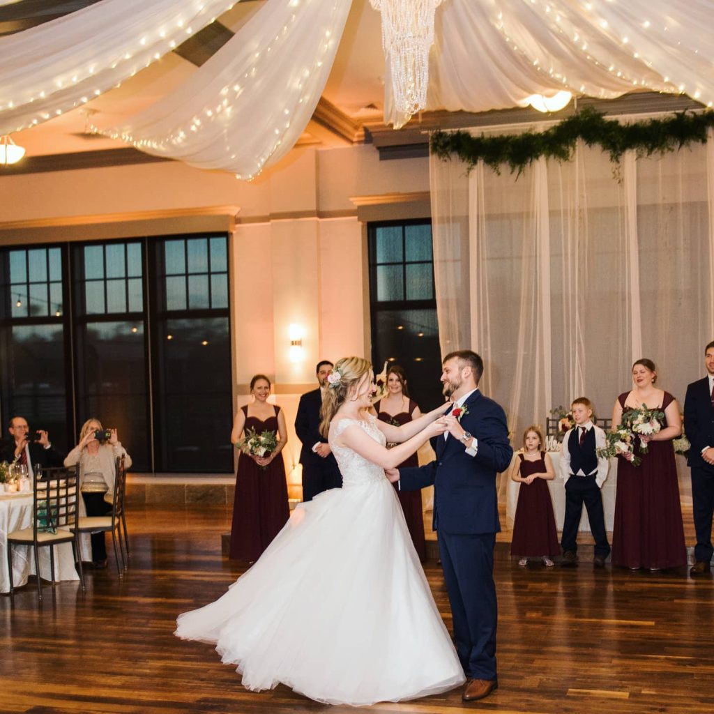 bride and groom dancing in ballroom under market lights and white swagged ceiling coordinated by Julie Miner Events