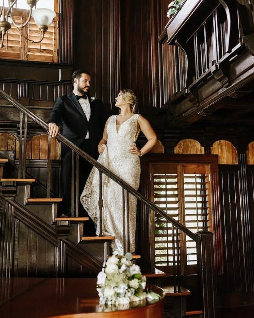 bride and groom on dark wooden stair case smiling at each other at event coordinated by Julie Miner Events