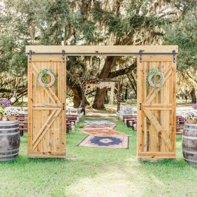 wooden barn doors leading to outdoor wedding ceremony site with rug aisle runners at The Red Barn at Bushnell