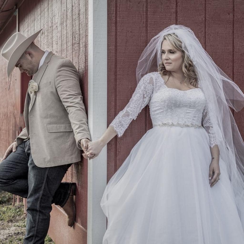 first look between bride and her groom wearing a cowboy hat and boots at the corner of The Red Barn at Bushnell