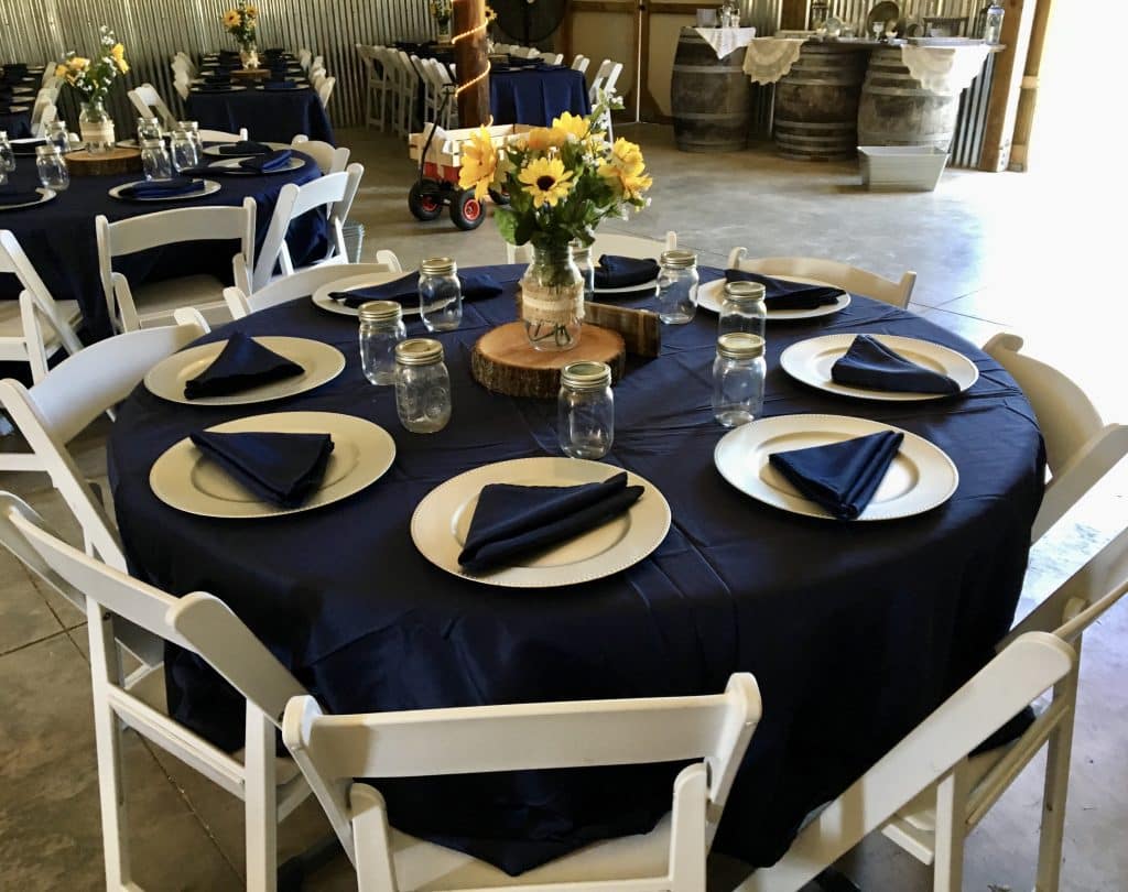 navy and white table rounds with white chairs and yellow daisy centerpieces at The Red Barn at Bushnell