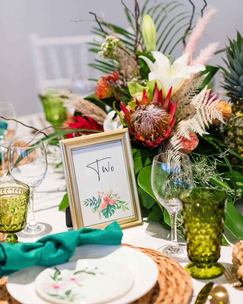 tropical table centerpiece with turquoise and pink accents and gold frame with table number coordinated by Julie Miner Events