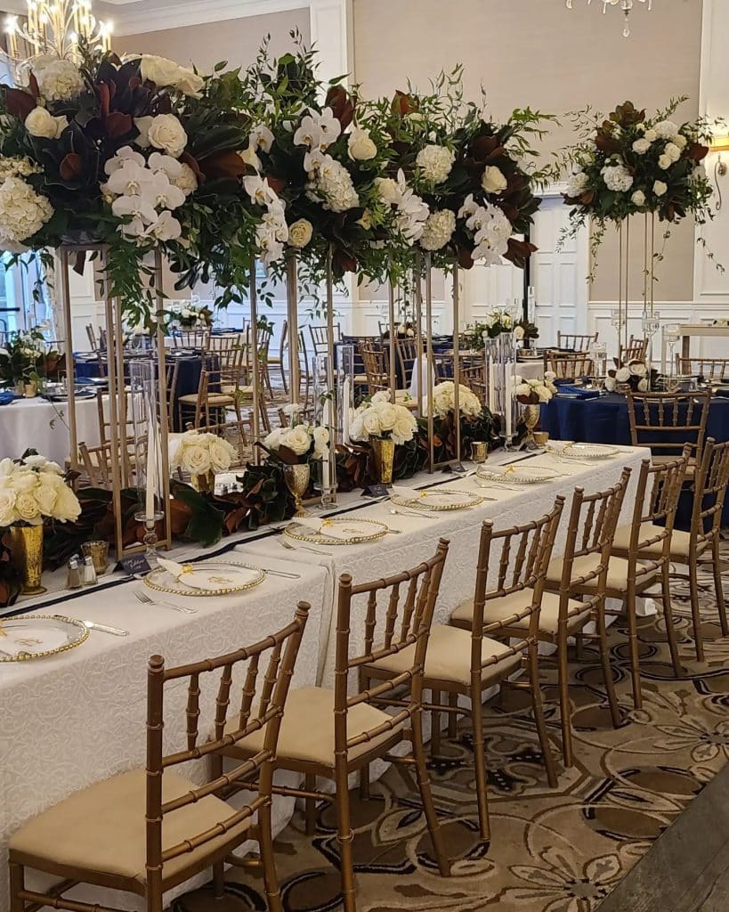 long tables with tall centerpieces and lower table runner of flowers by Ian Tafoya Designs