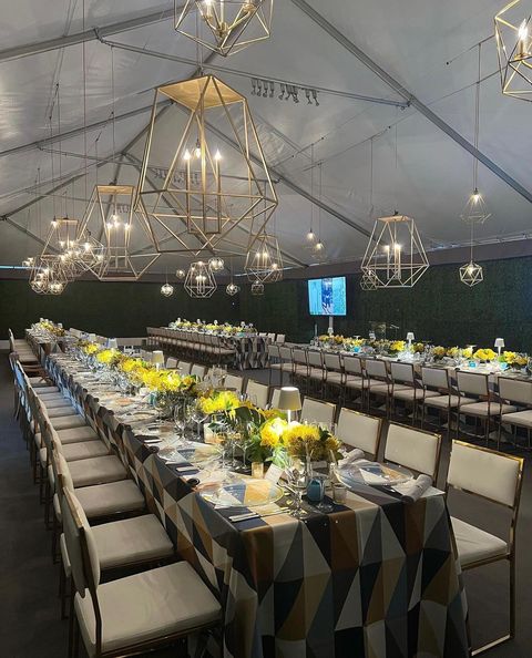 untra long tables and chairs under large tent from Bubble Design Rentals Orlando with bright yellow centerpieces