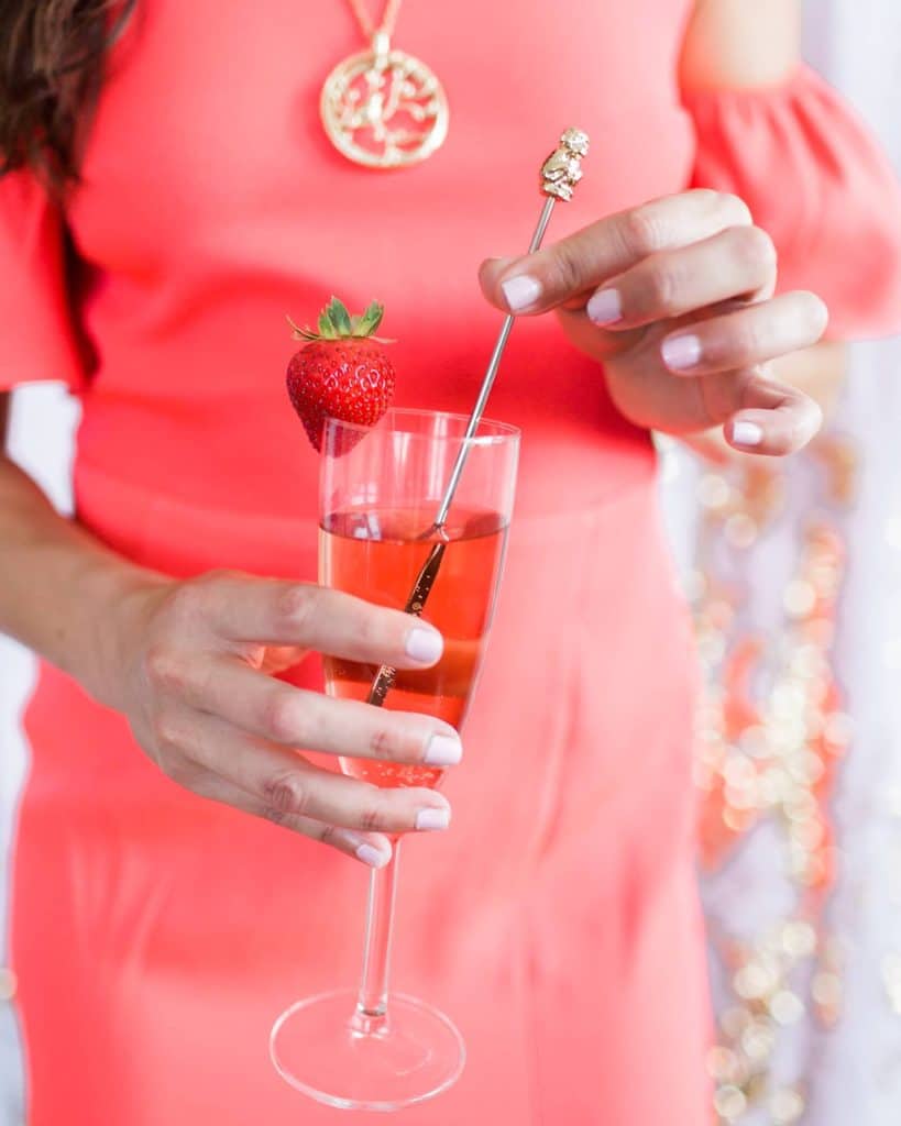 wedding guest in pink dress holding strawberry mimosa that matches her dress coordinated by Julie Miner Events