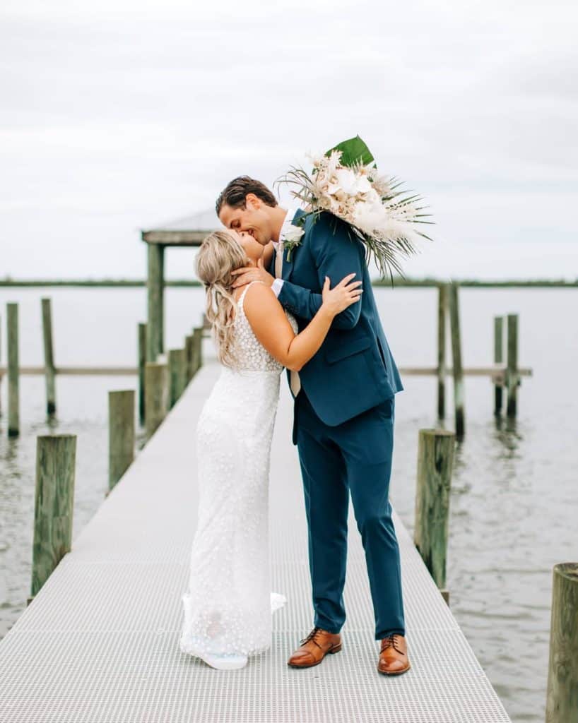 bride on a dock wrapping her arms and her bouquet around her groom to kiss him coordinated by Julie Miner Events