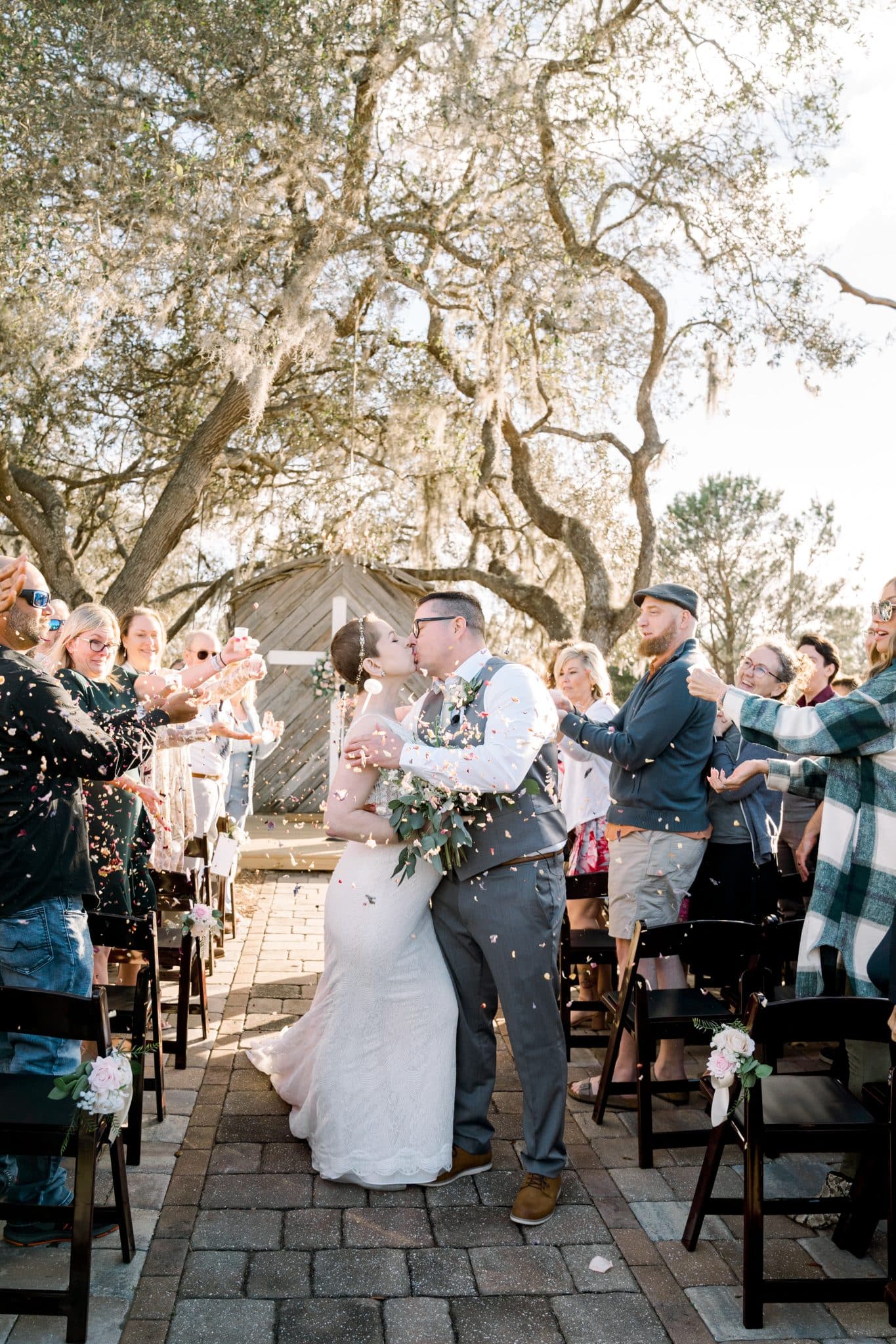 After the wedding vow renewal ceremony, the couple kisses as guests throw confetti.