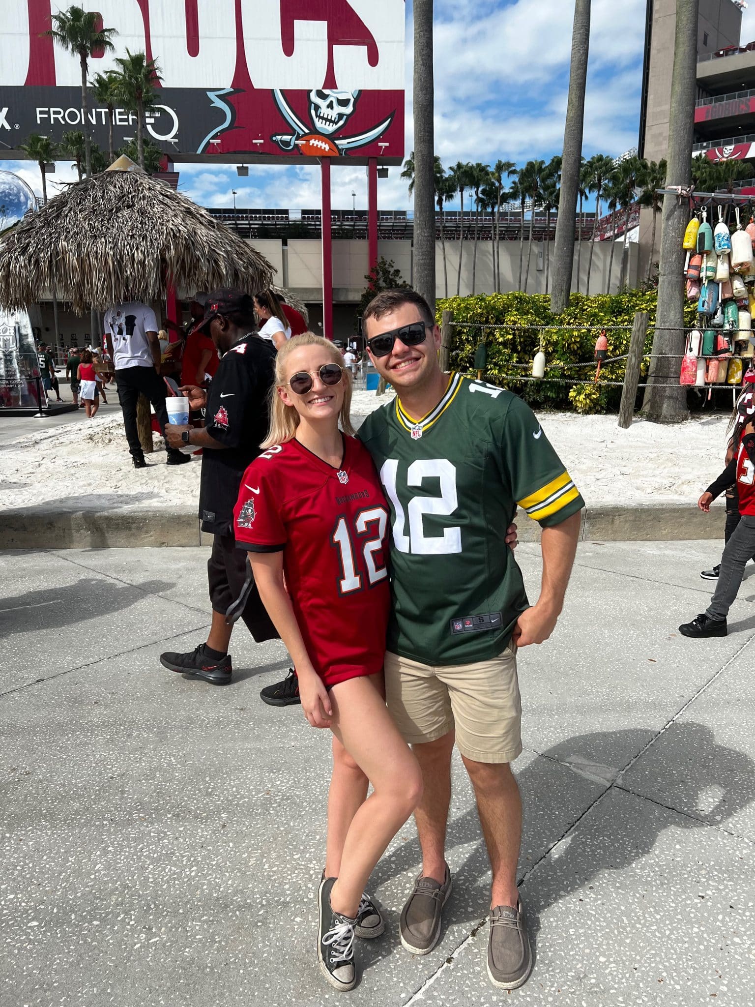 couple stands outside of stadium wearing Tampa Bay Buc's jersey and Green Bay Packers Jersey