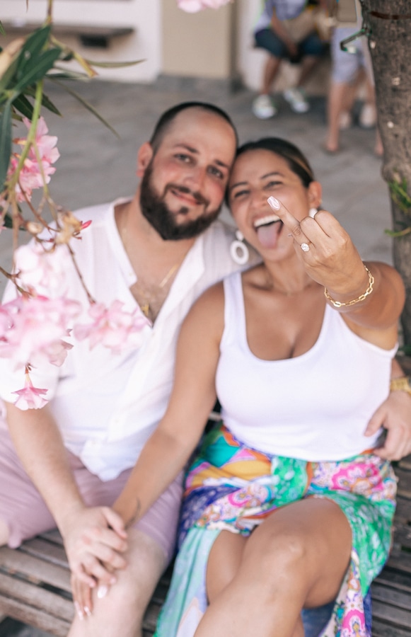 Newly engaged couple poses for a photo, Nicolle shows her ring finger adorned with diamond ring