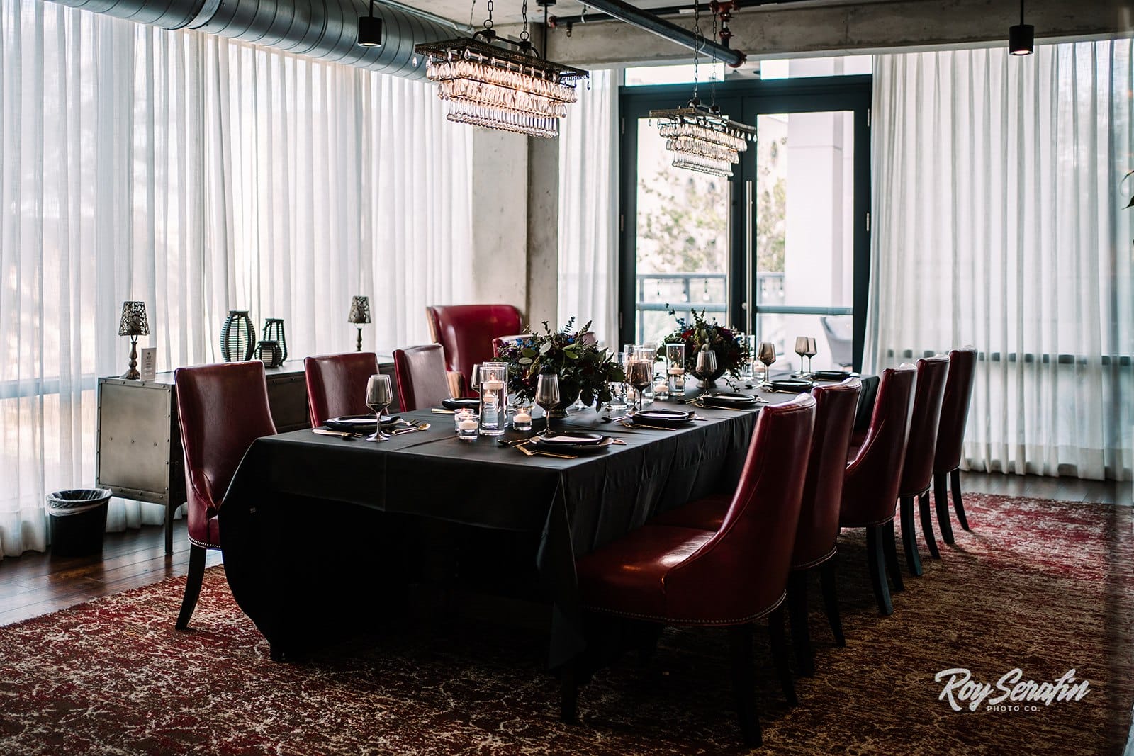 private dining table in room with bright red chairs and black linen set for nice dining with floral and candles in the middle of the table as well