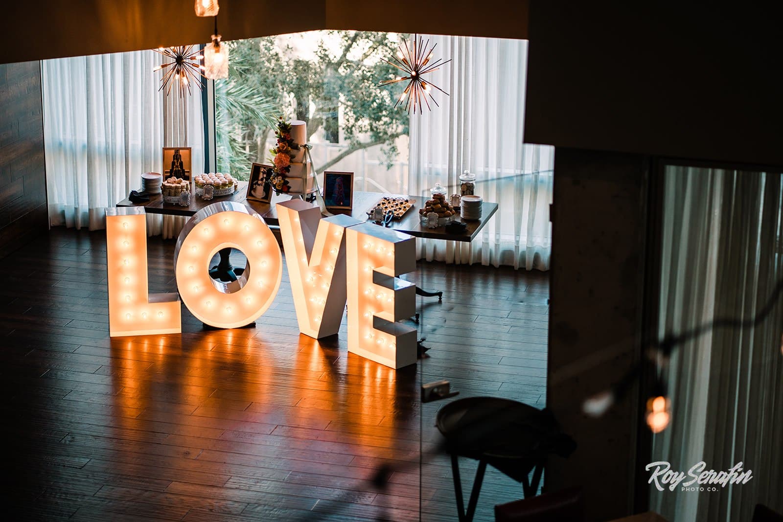 picture from above of dessert table setup with wedding cake in the middle and giant marquee letters setup in front of the table spelling out the word love