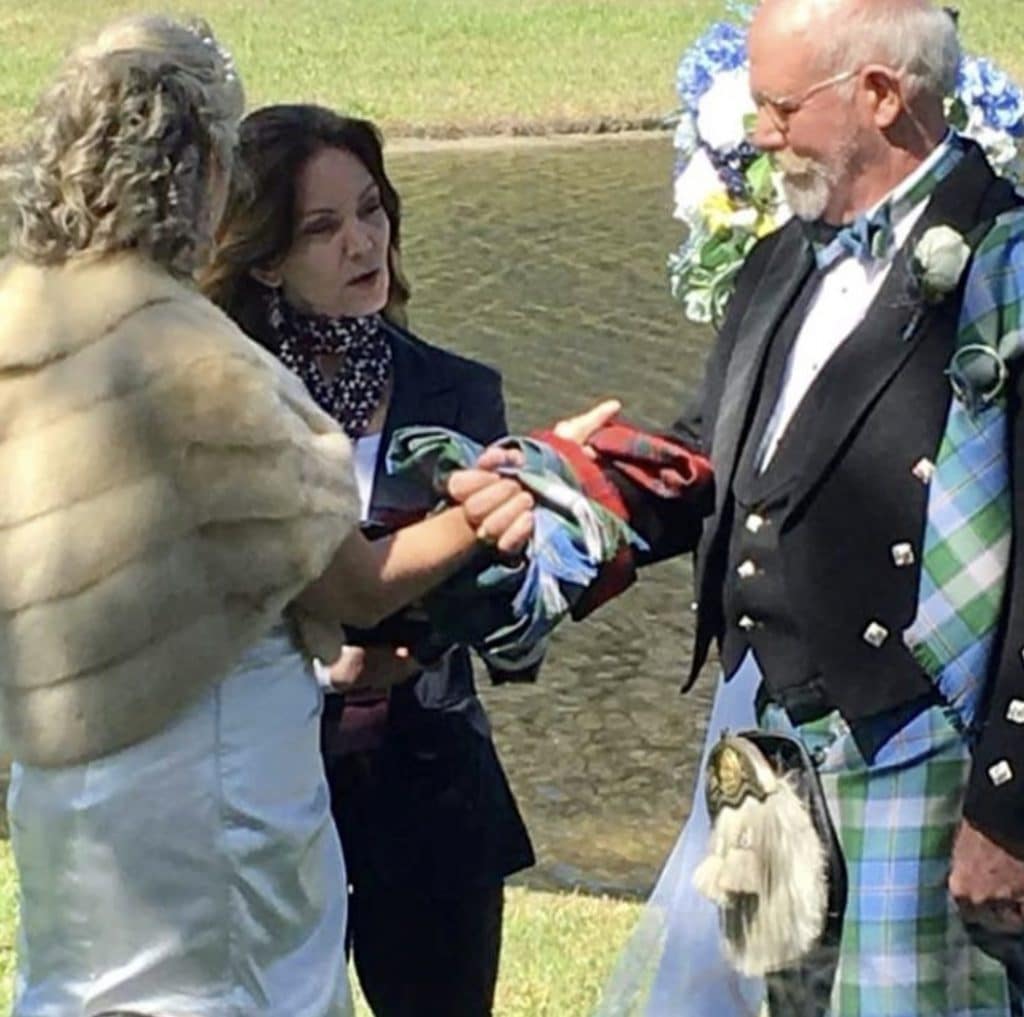 groom in kilt and bride in faux fur stole handfasting with officiant from Freebird Ceremonies