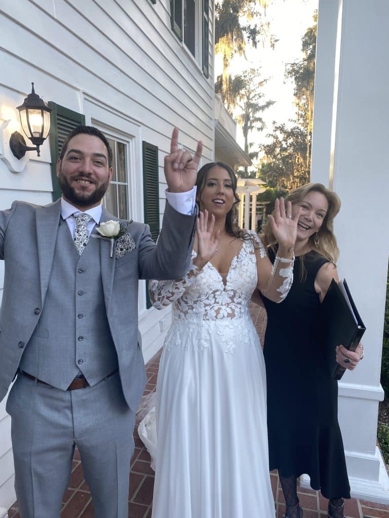 bride and groom holding up 'rock on' fingers with officiant from Freebird Ceremonies