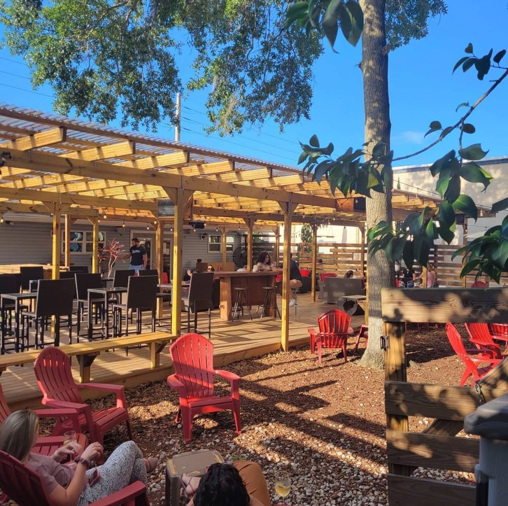 outdoor patio with oak trees and adirondack chairs at the Grape & The Grain Wine Bar