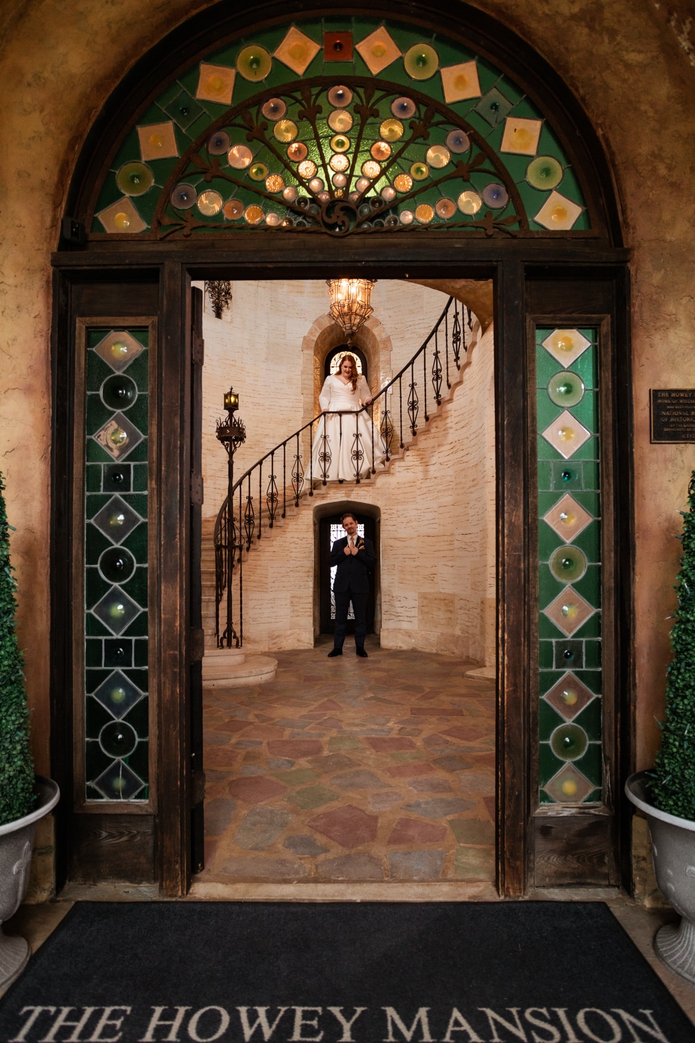 Bride and groom pose for photos in front of stunning entryway at The Howey Mansion wedding venue in Central Florida