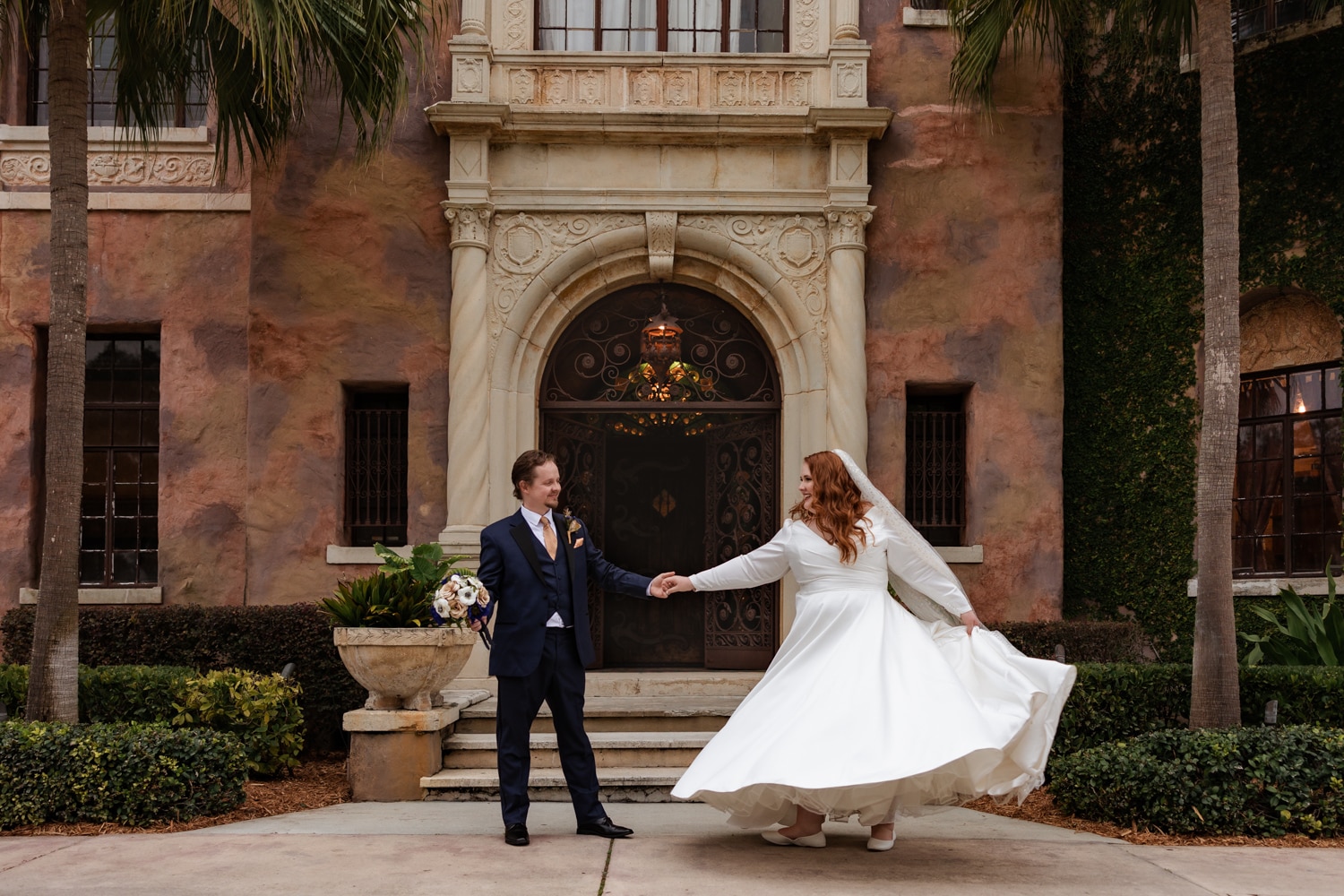 newlyweds hold hands in a spin dance move in front of Florida's Howey Mansion wedding venue