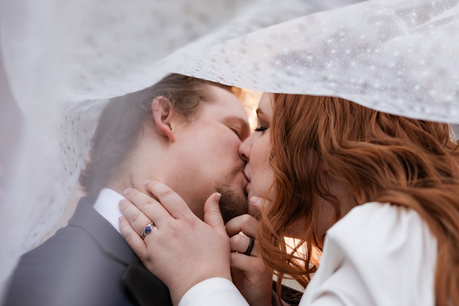 Newlyweds share a kiss under bride's DIY veil at celestial wedding at The Howey Mansion