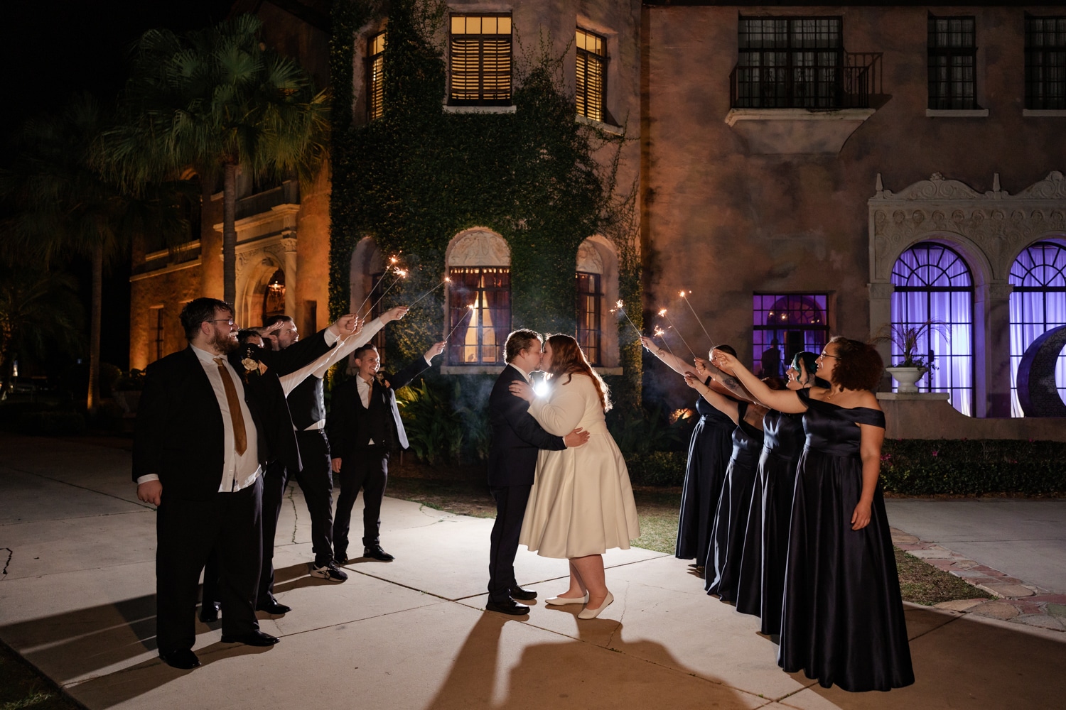 Bride and groom newlyweds kiss as they exit their celestial wedding at Howey Mansion under sparklers.